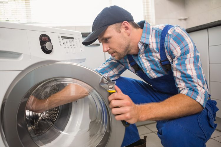 Handyman fixing a washing machine in the kitchen